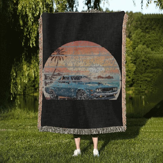 A muscle car cruisingon a coastal road. Woven Blankets